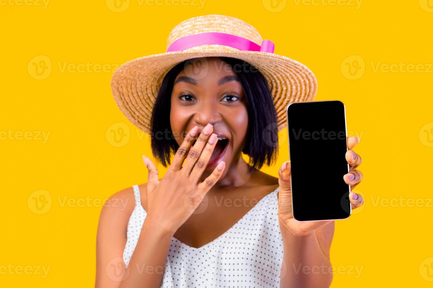 Online sale. Emotional black lady showing cellphone with empty screen, covering mouth in shock on orange studio background, mockup for mobile app or website. Selective focus photo