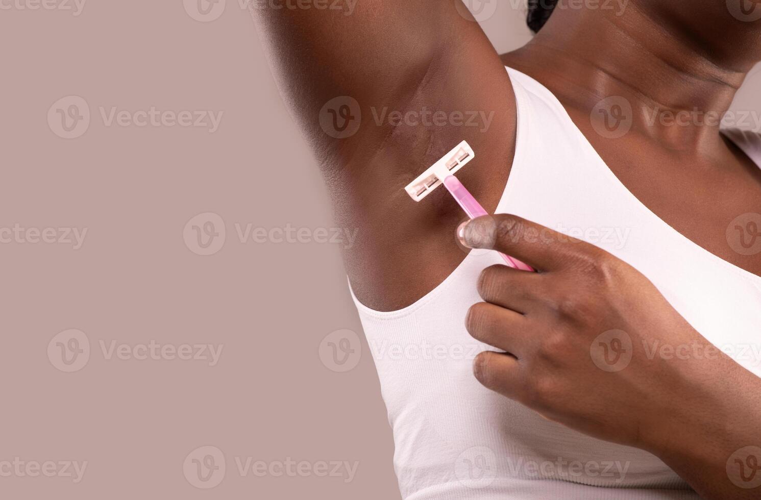 Hair Removal. Unrecognizable Black Woman Shaving Her Armpit With Pink Razor, African American Female Making Underarm Depilation, Standing Isolated Over Grey Background, Closeup, Copy Space photo