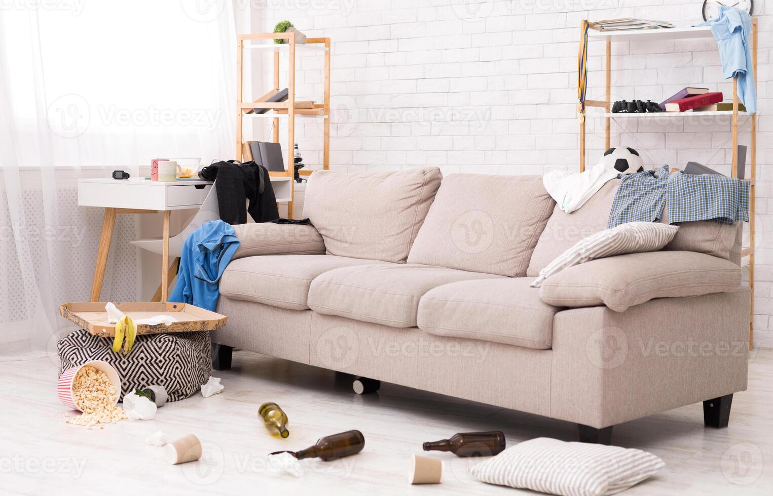 After party. Chaos and mess in room, clothes, food and bottles on the floor and sofa, copy space photo
