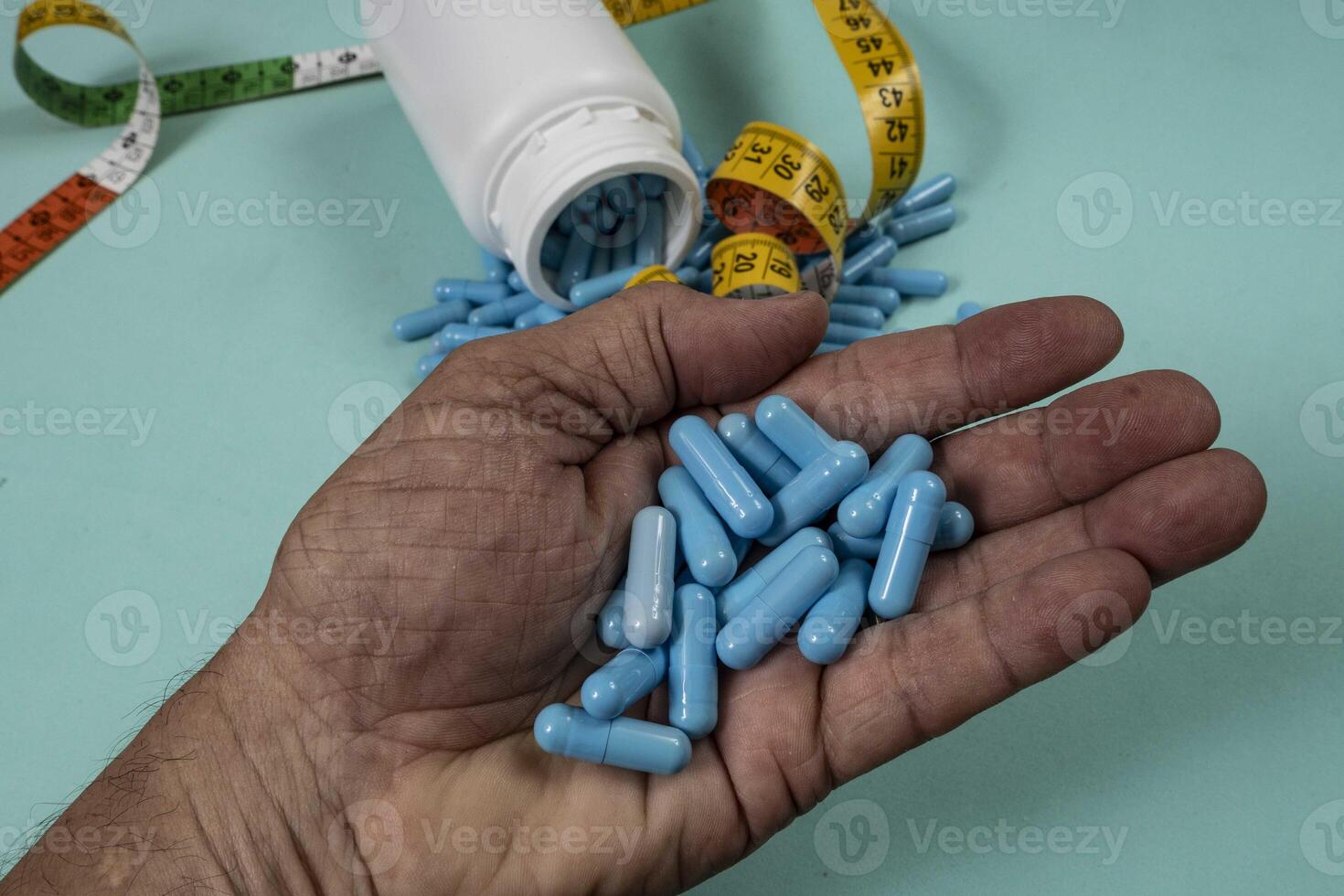 bottle of pills, some of which spilled onto a light blue surface 2 photo
