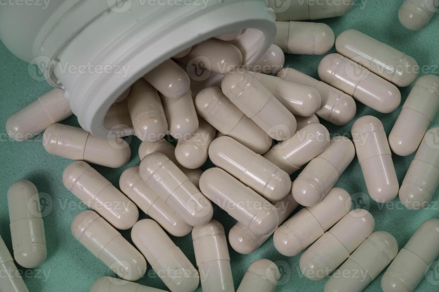 bottle of pills, some of which spilled onto a light blue surface 3 photo