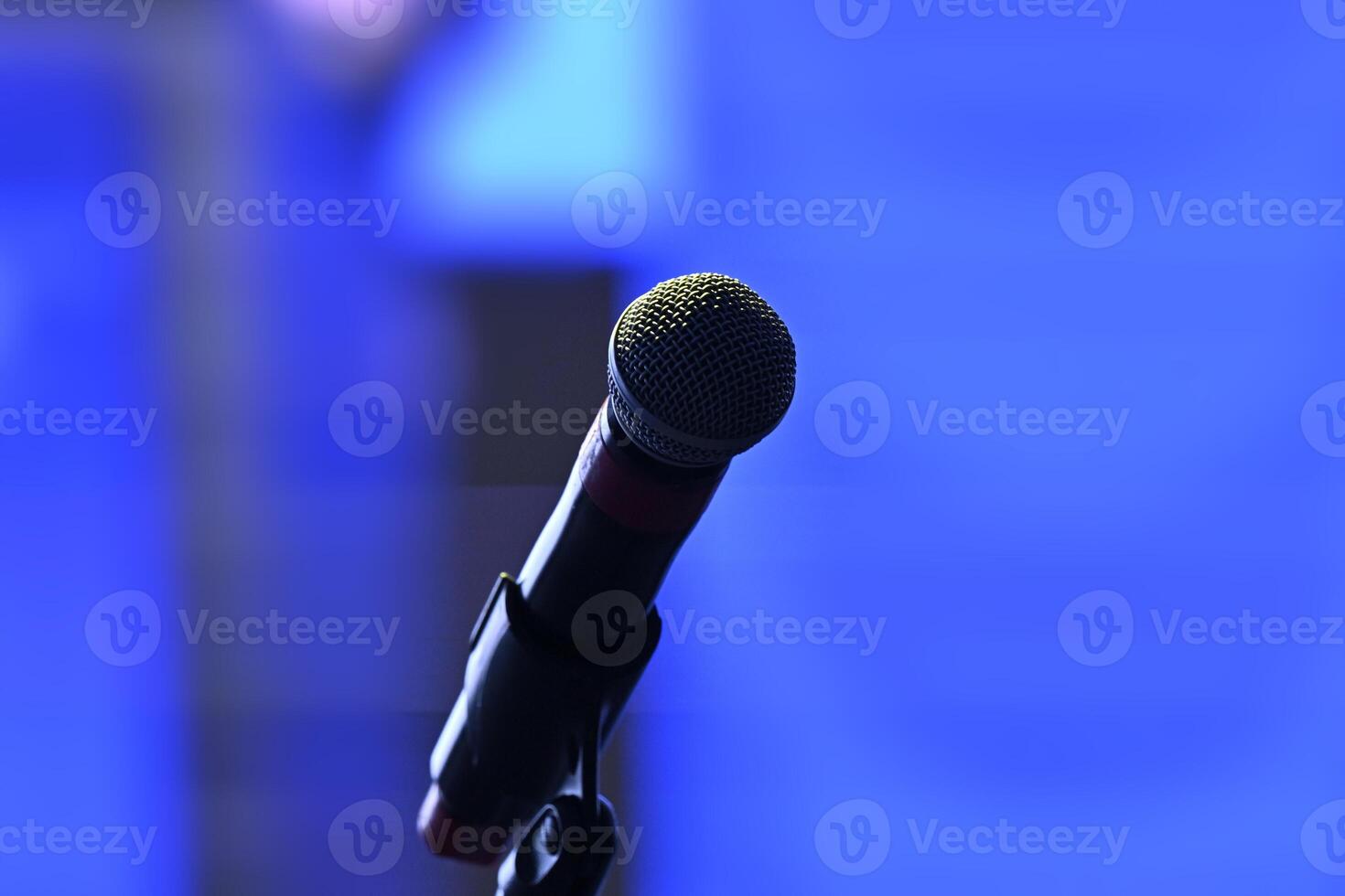Spherical head of a stage microphone in a blurred environment. Dark lighting and blue background photo