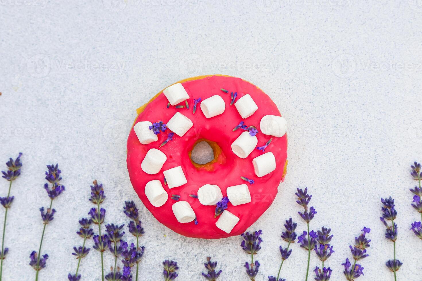 Colorful donut topped with mini marshmallows and lavender on a light background photo