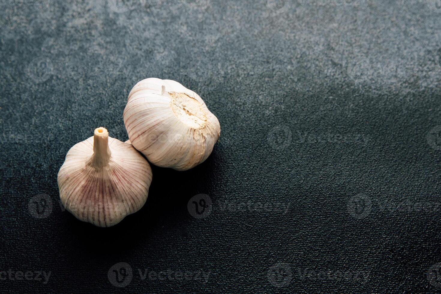 Garlic bulbs placed on a dark textured surface for culinary preparations in a kitchen photo
