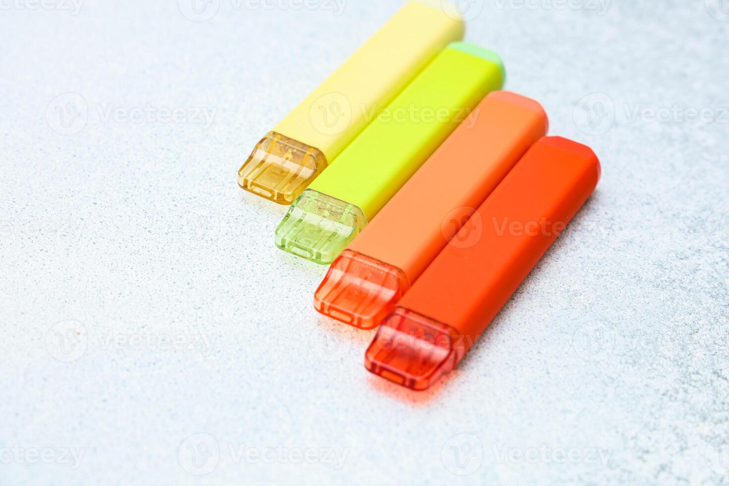 Colorful disposable electronic cigarettes arranged neatly on a light surface photo