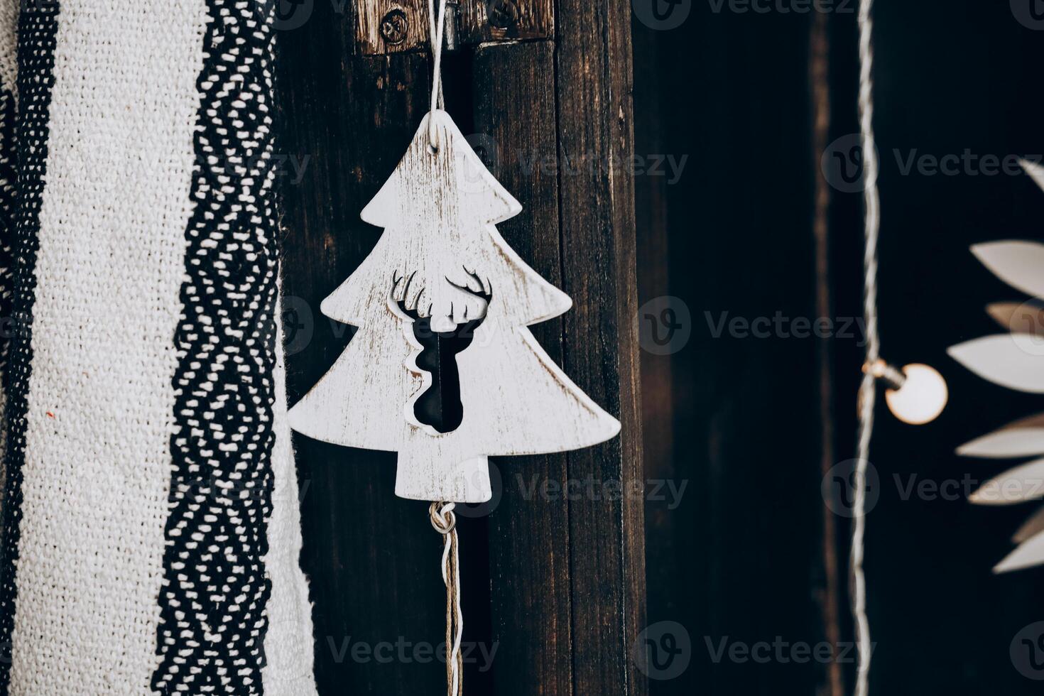 Decorative Christmas ornament shaped like a tree with a deer motif hanging on a wooden background photo