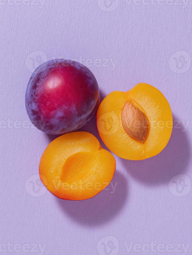 Minimalist flat lay of ripe plum and halved purple fruit on pastel background for summer design photo