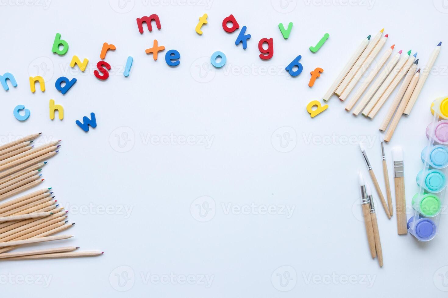 Colorful alphabet magnets and art supplies on white background photo
