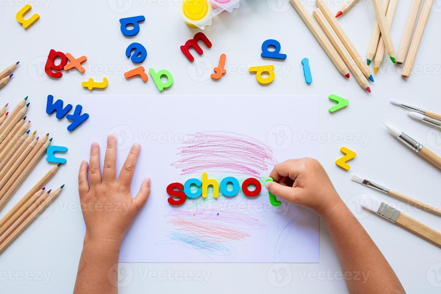 Children hands arranging colorful alphabet letters for learning activity photo