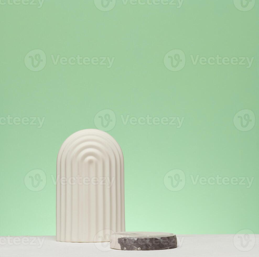 A white decorative element in an arched shape is installed on a green stone. A stage for demonstration and advertising photo