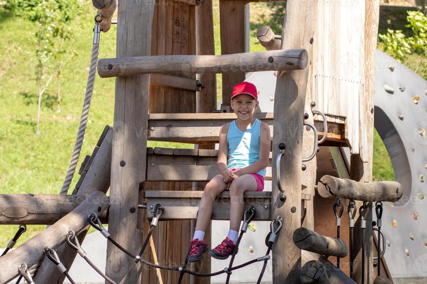 Happy and smiling caucasian child 7 8 years sitting on wood playscape looking at camera photo