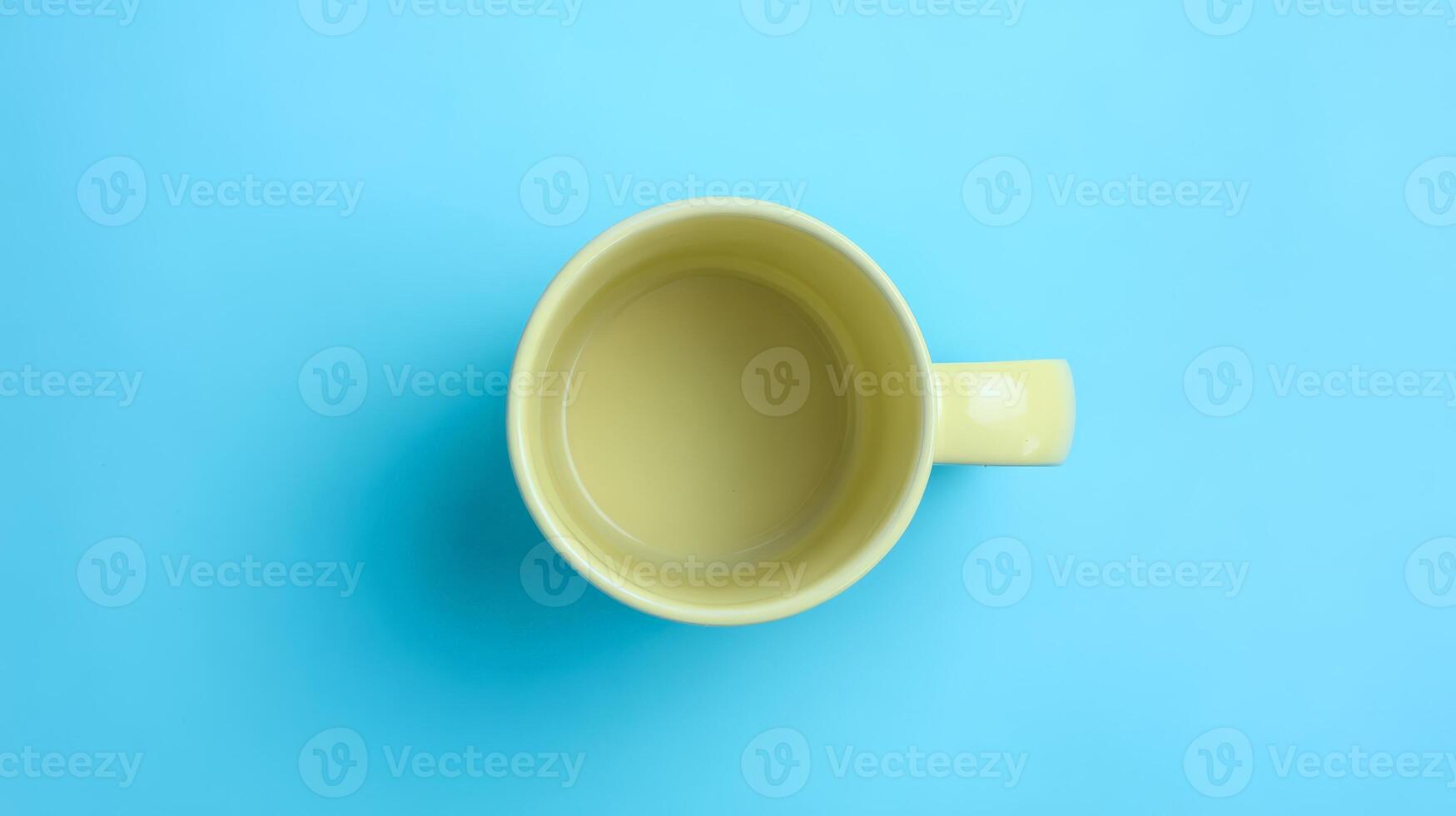 Empty Pastel Yellow Mug on Bright Blue Background photo