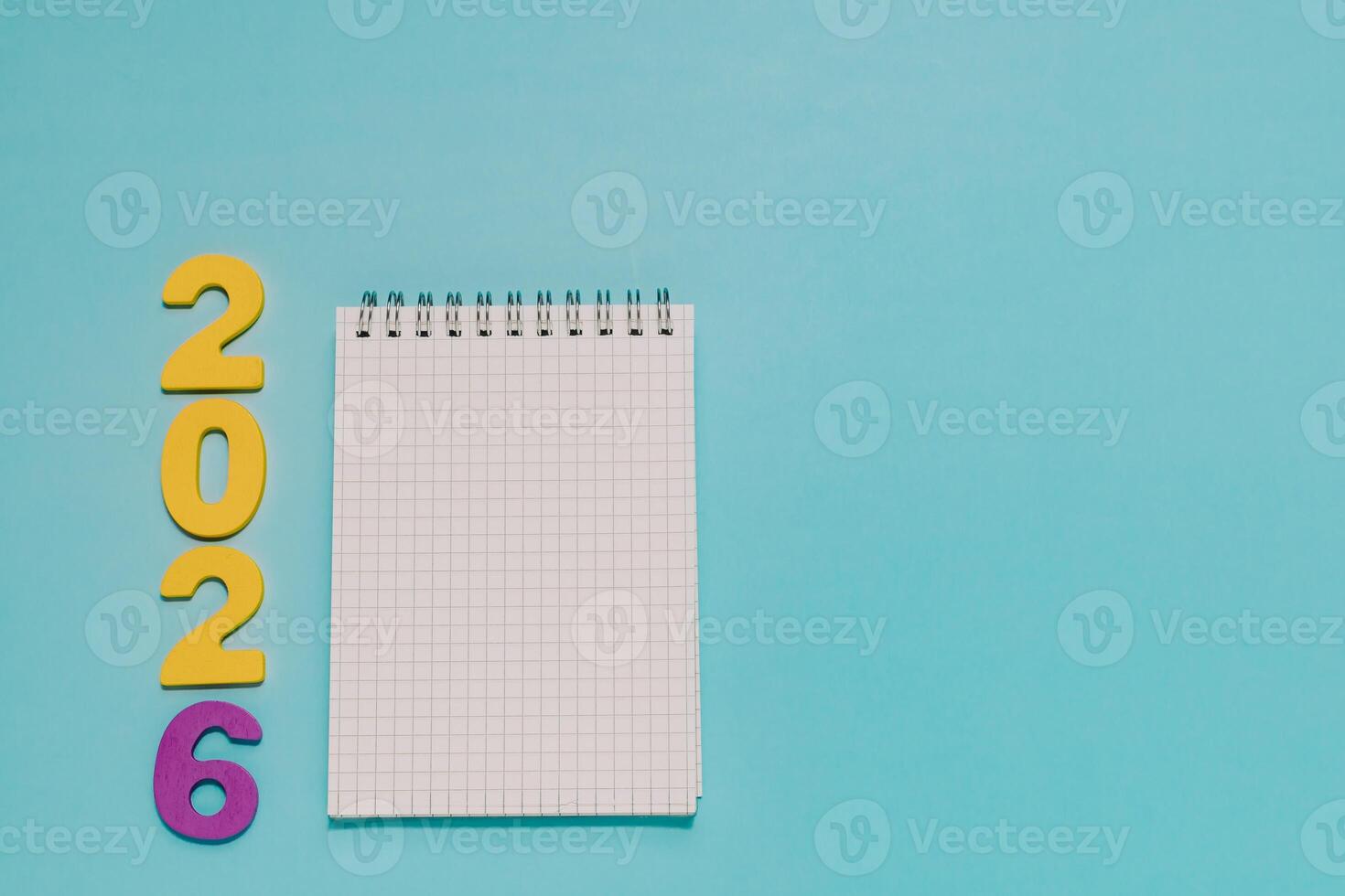 Yellow and purple 2026 next to a blank grid notepad on vibrant blue. Ideal for New Year planning, goal setting, resolutions, and 2026 events. photo