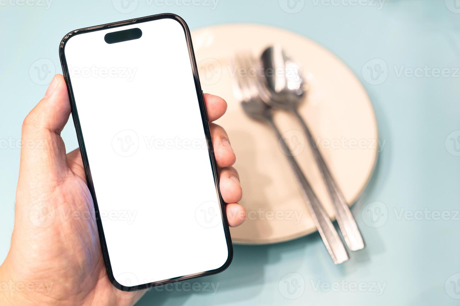 Hand holding smartphone with a blank white screen. Ordering Food Online with Smartphone. online food ordering, restaurant apps. The empty screen provides space for adding graphics or text. photo