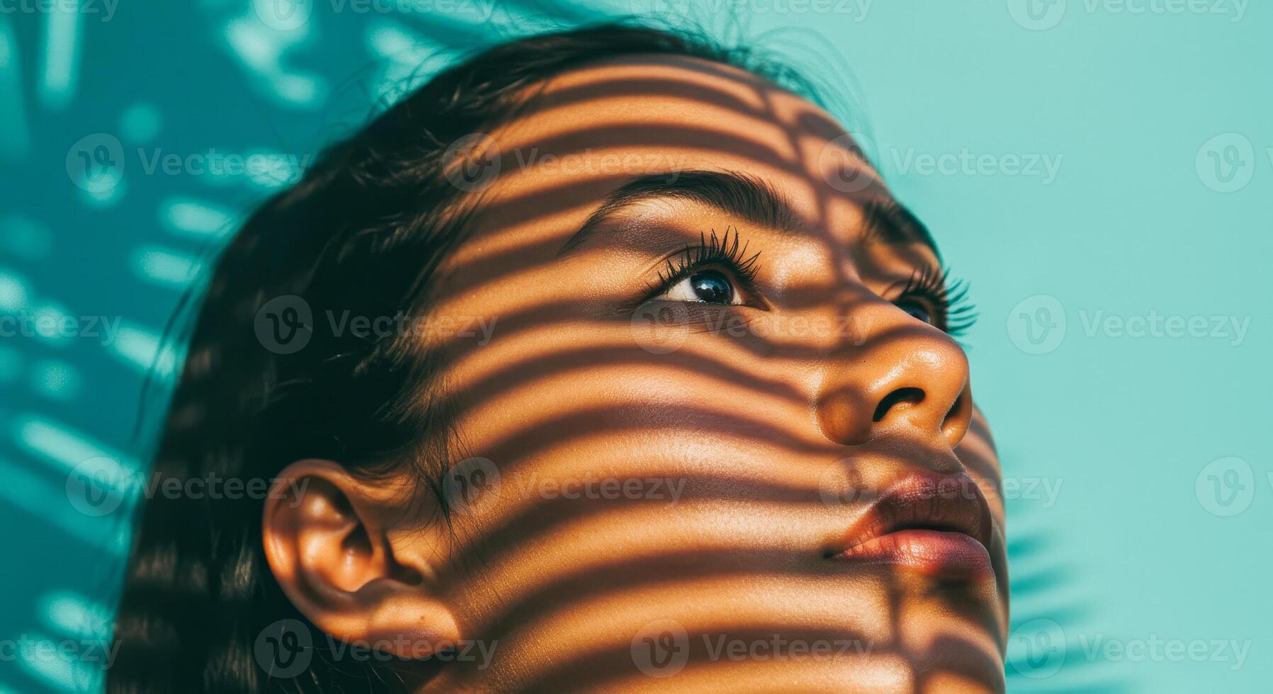 woman gazes upwards shadowed by vertical sunlight stripes. photo