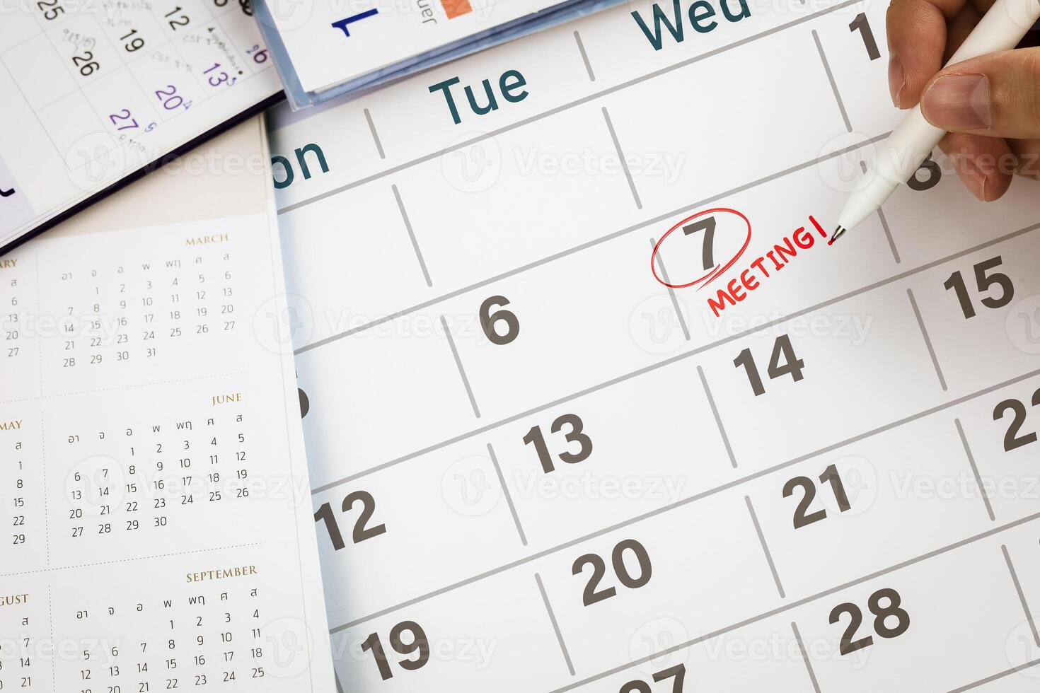 Close-up view of hand using pen to draw red circle on calendar with write word Meeting. Concept of appointment reminder, meeting agenda, and mission schedule. photo