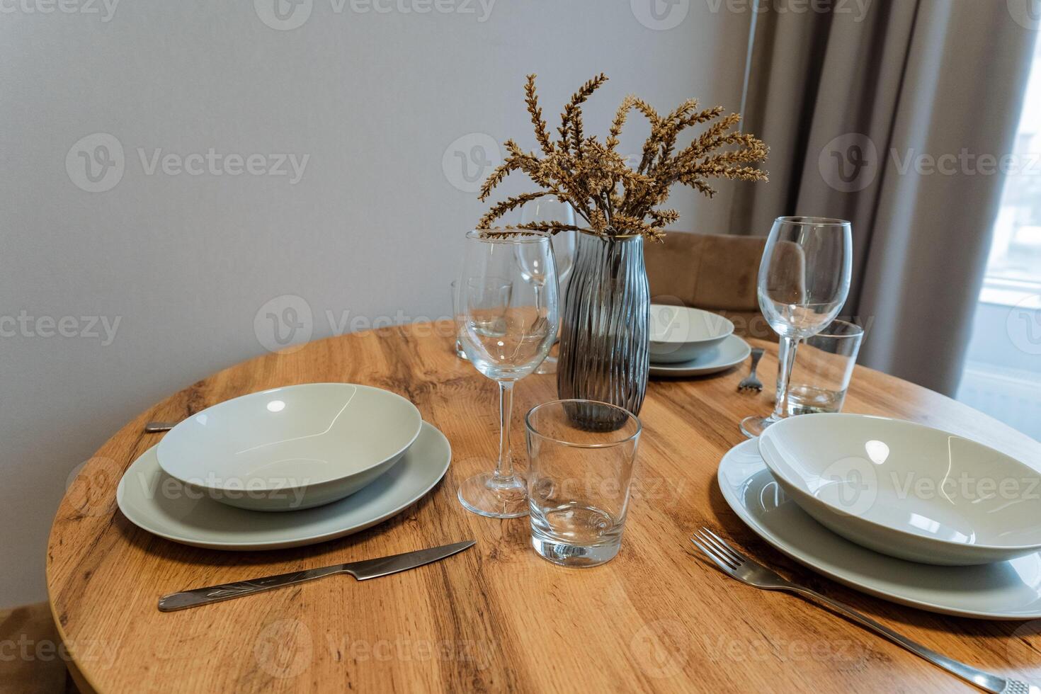 A beautifully crafted wooden table featuring an array of plates, glasses, and a lovely vase filled with colorful flowers elegantly placed on it for a delightful dining experience photo