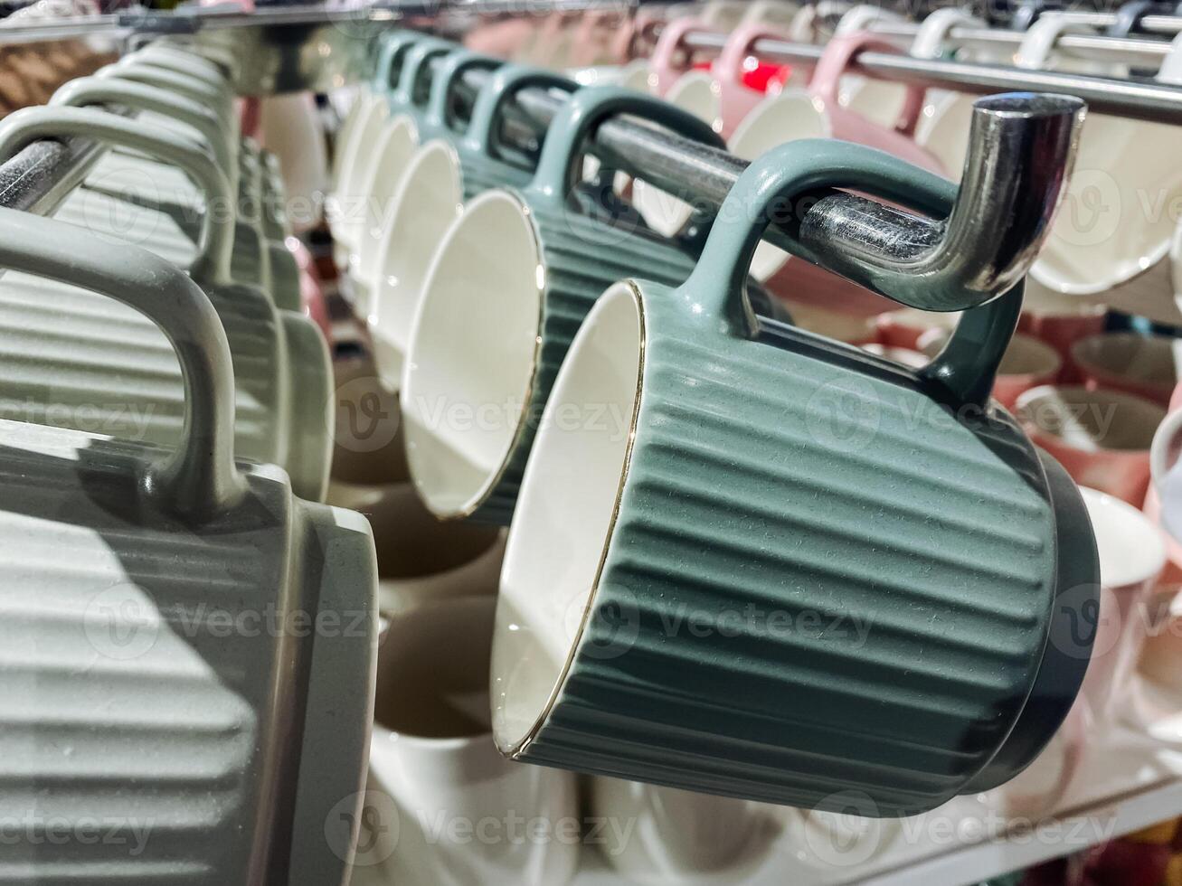 There is a beautiful row of colorful coffee mugs gracefully hanging on a sturdy rack displayed in the store for customers to admire and possibly purchase for their homes or kitchens photo