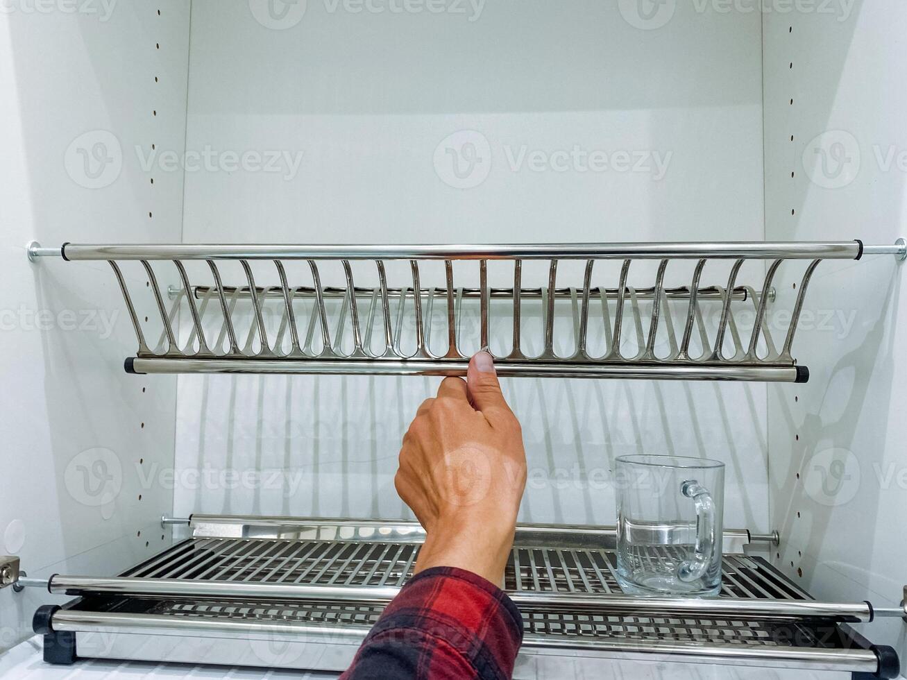 A person is extending their hand to retrieve a glass from a dish rack that is located in the kitchen, where various kitchen utensils and appliances are stored and organized photo