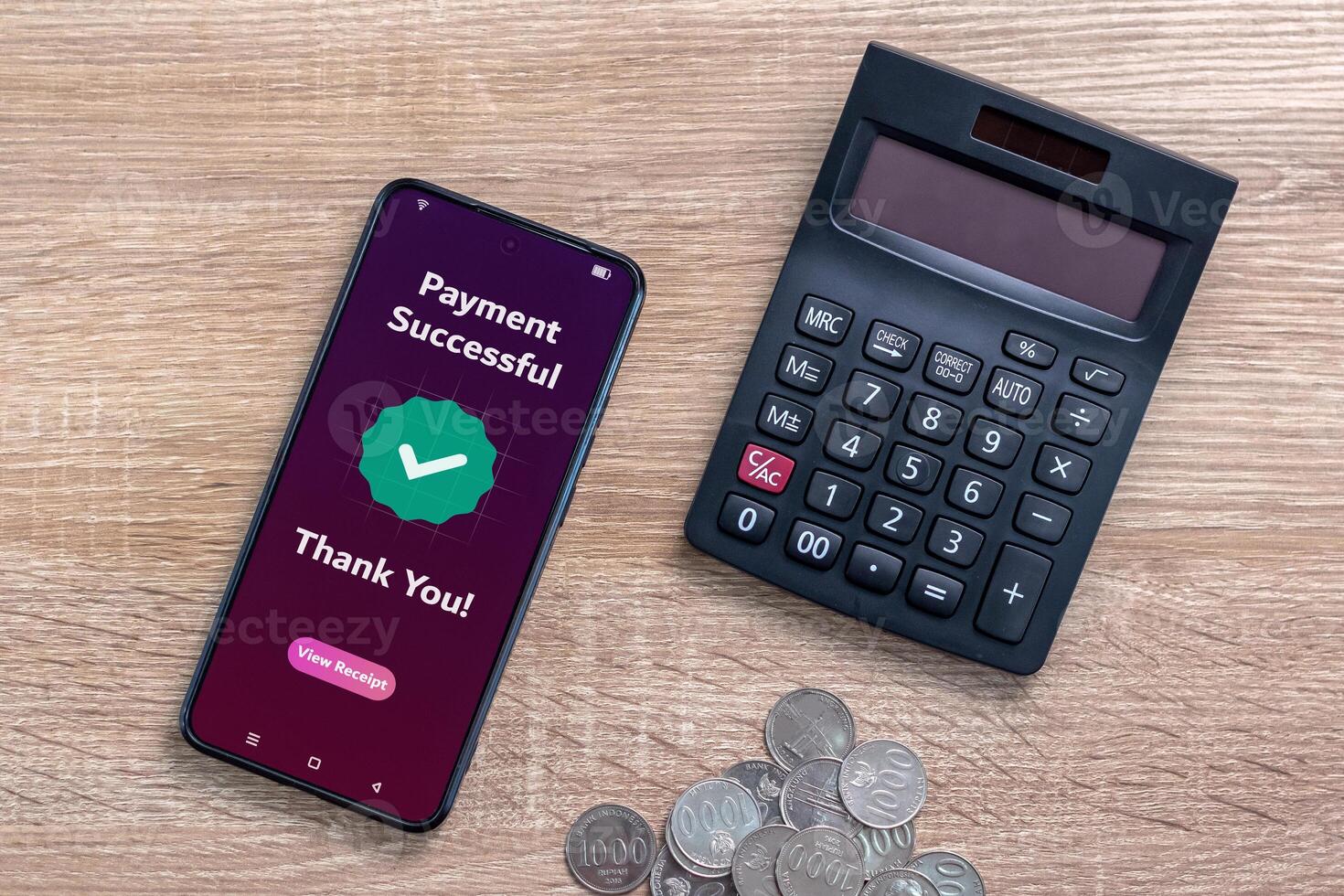 A smartphone, calculator, and coins on wooden table. Online payment successful concept. photo