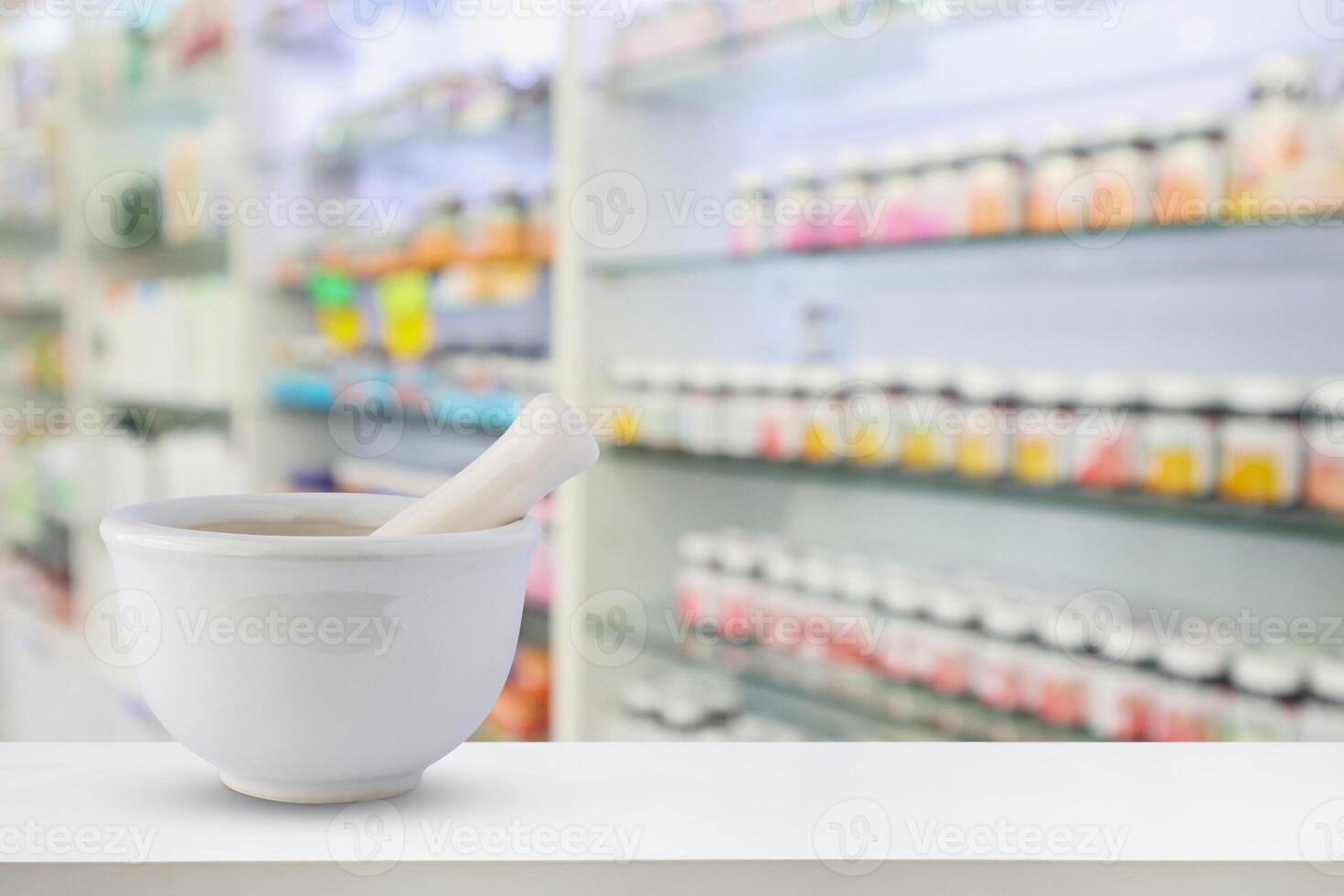 A white mortar and pestle sitting on a table in front of shelves of medicine photo