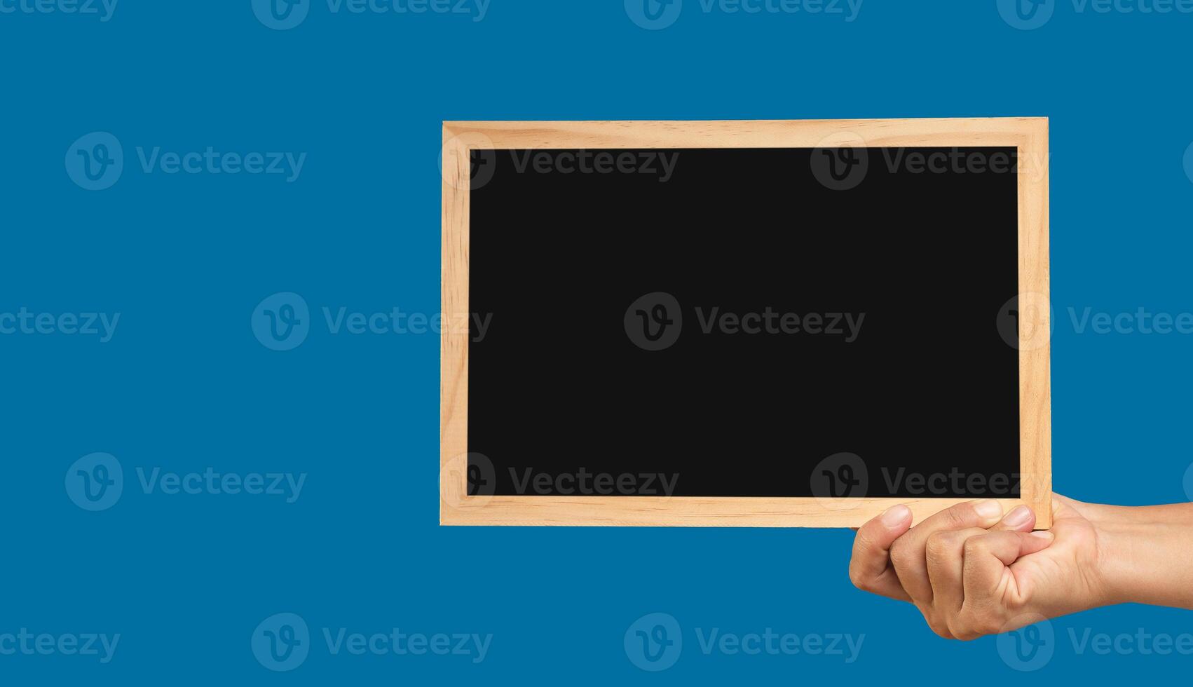 Hand holding a mini chalkboard against a blue background photo