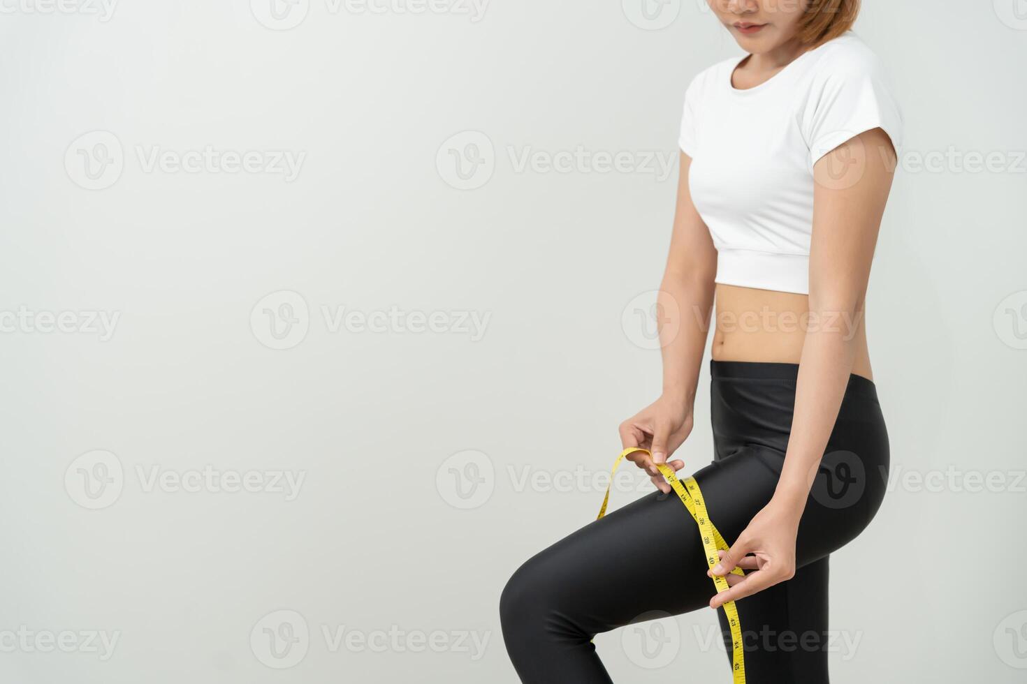 Diet and dieting. Beauty slim female use tape measure of thigh. Woman in exercise clothes achieves weight loss goal for healthy life, crazy about thinness, nutritionist. photo