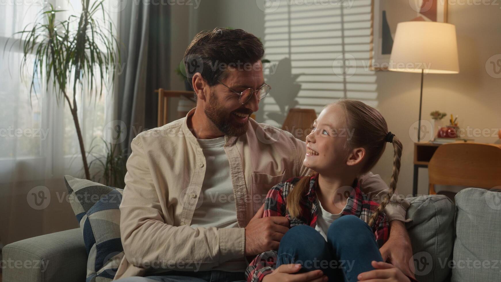 Caucasian happy family at home on couch smiling child kid girl daughter with daddy man father together smile relaxing sitting on sofa laughing enjoying weekend bonding relationship in living room photo