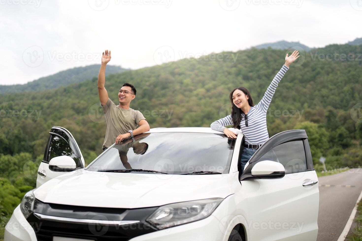 Adventure Awaits. Friends waving from car roof in scenic landscape. photo