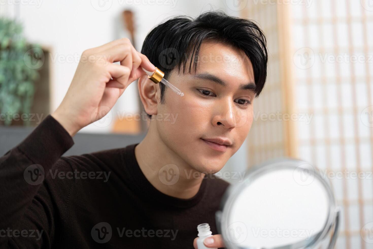 Skincare Routine. Young man applying serum for glowing skin. photo