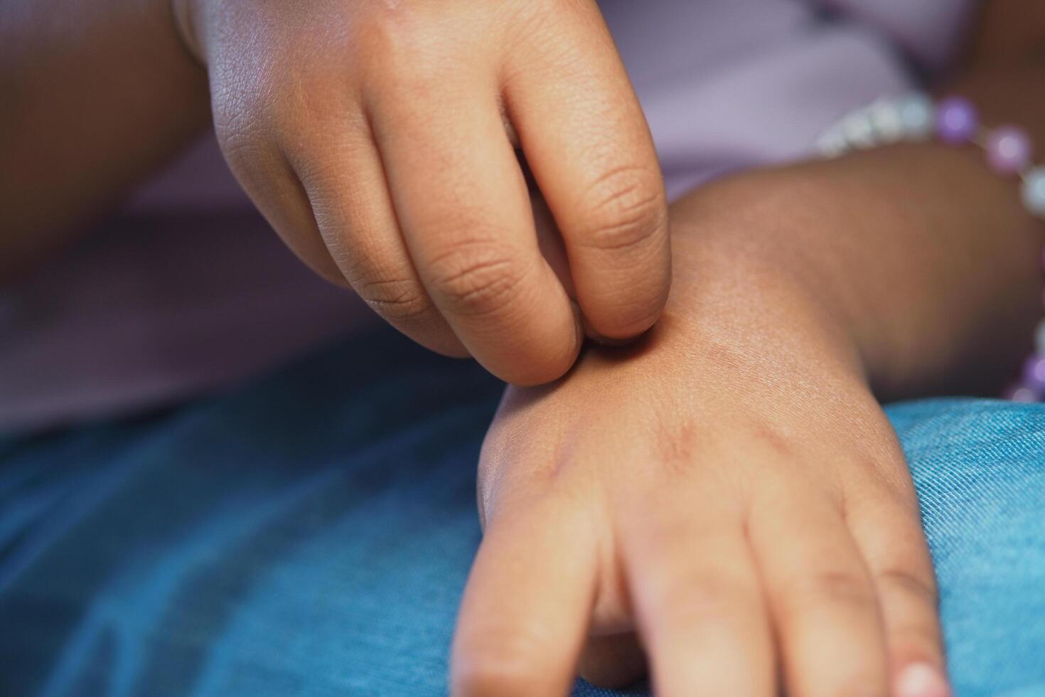 Child scratching arm in a relaxed setting during daytime photo