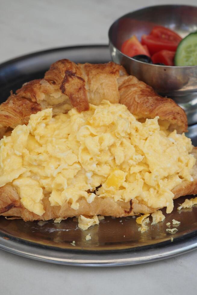 Scrambled eggs served in a flaky croissant at brunch photo