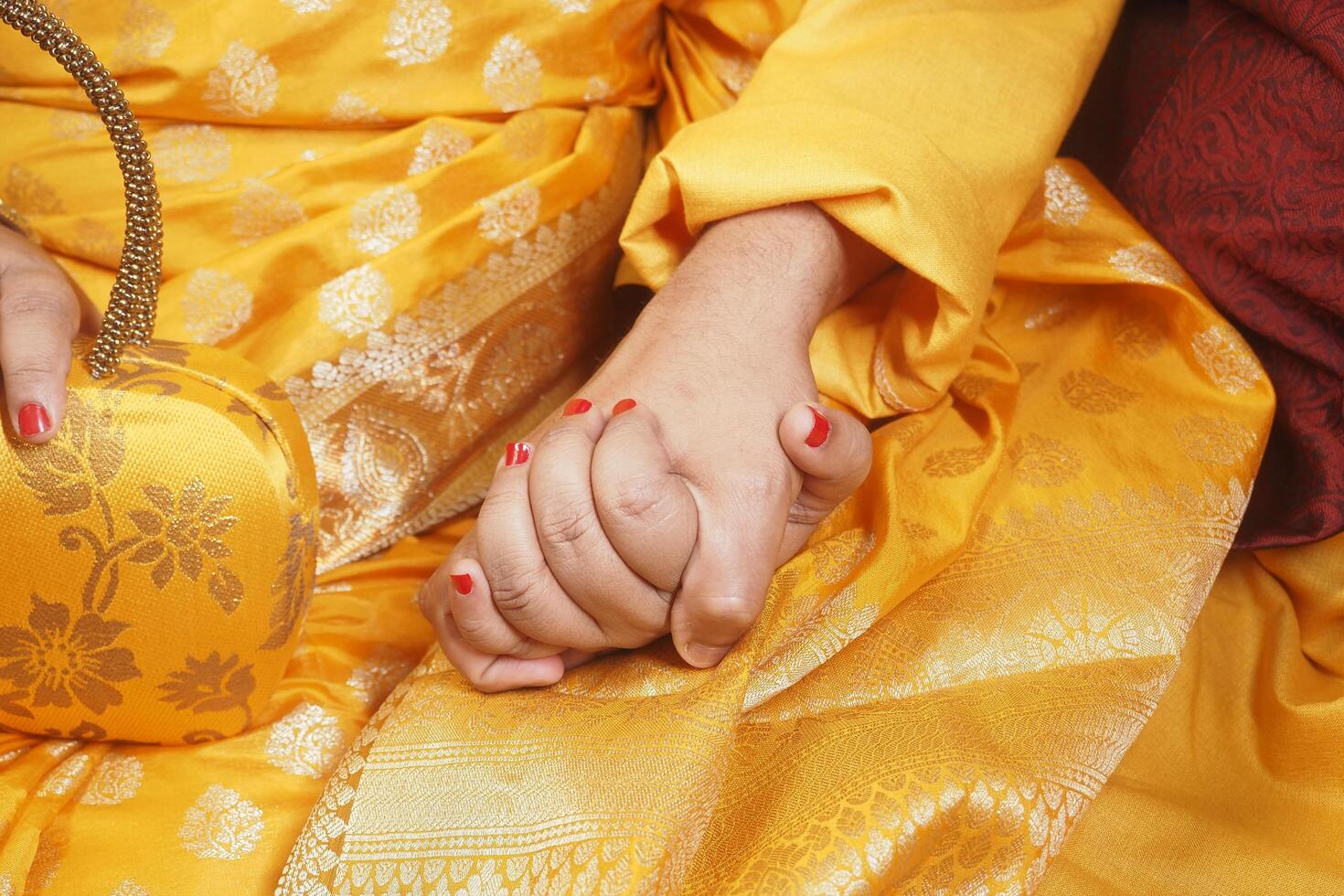 Couple in traditional attire holding hands for celebration photo