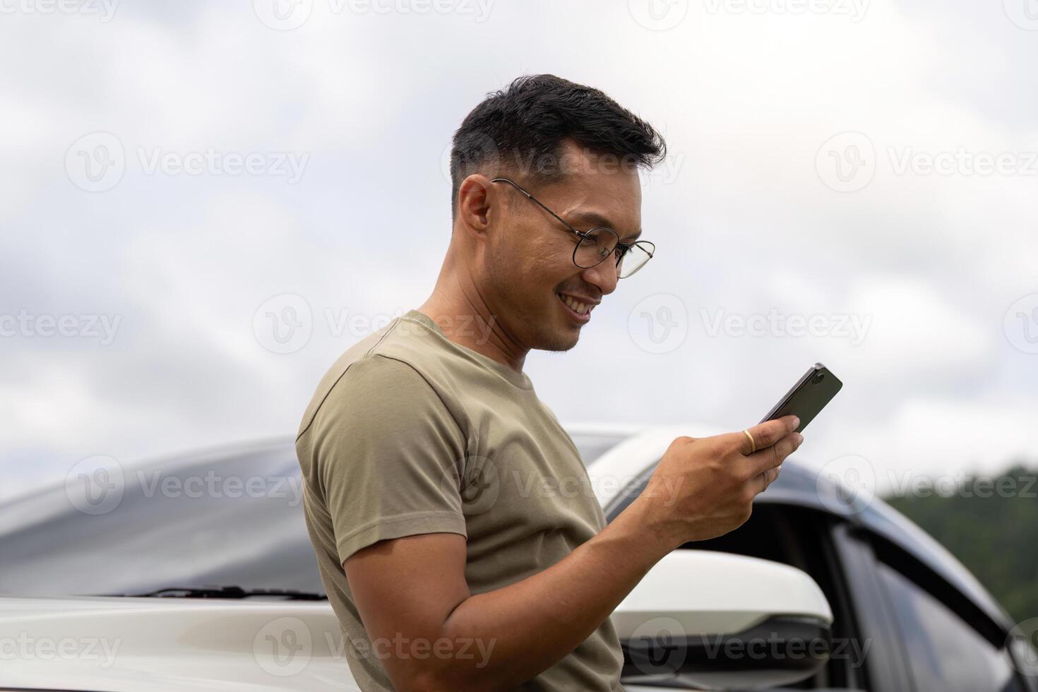 Digital Connection. Young man using smartphone outdoors near car. photo
