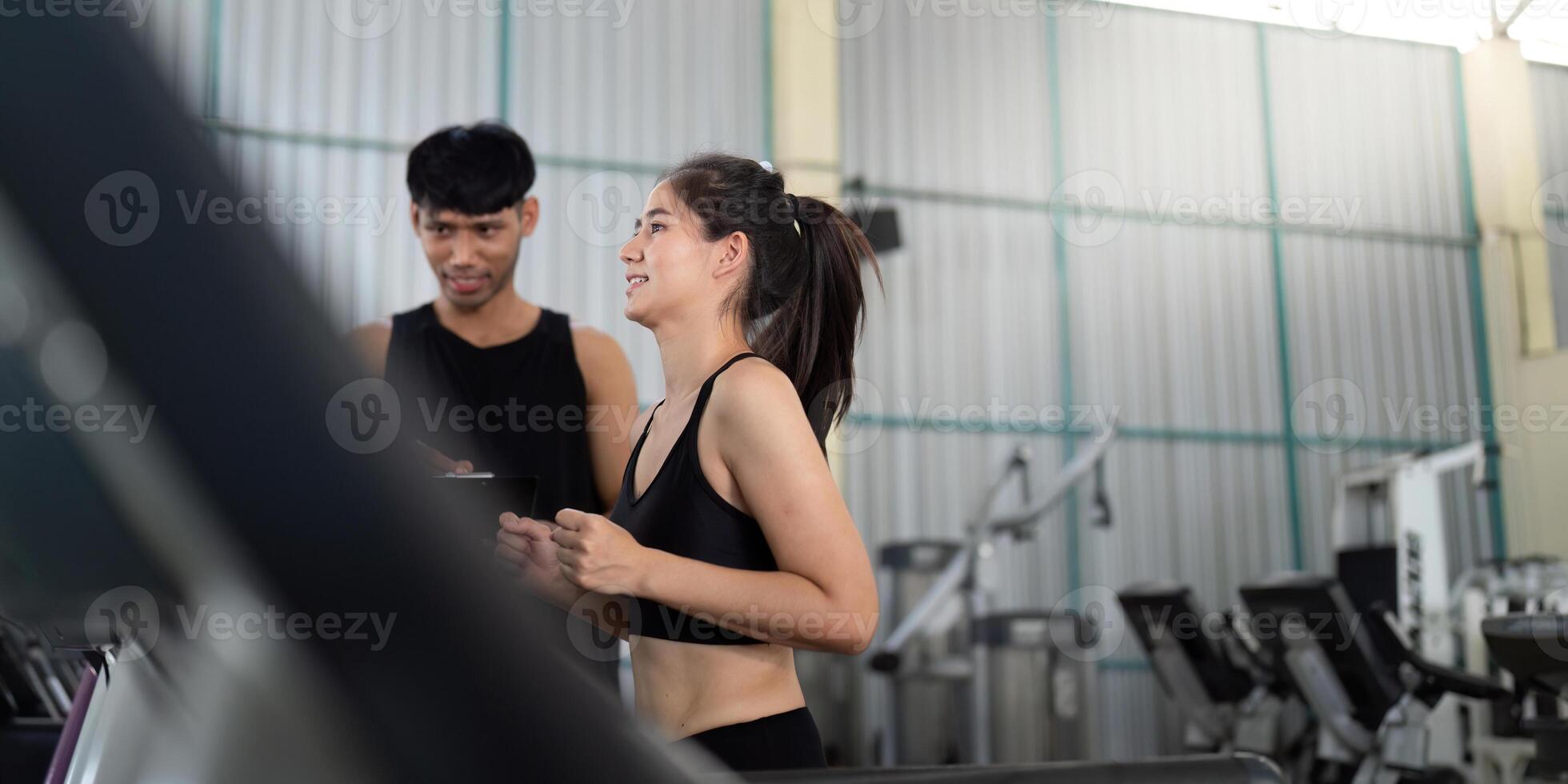 Trainer assisting female athlete in gym workout session photo