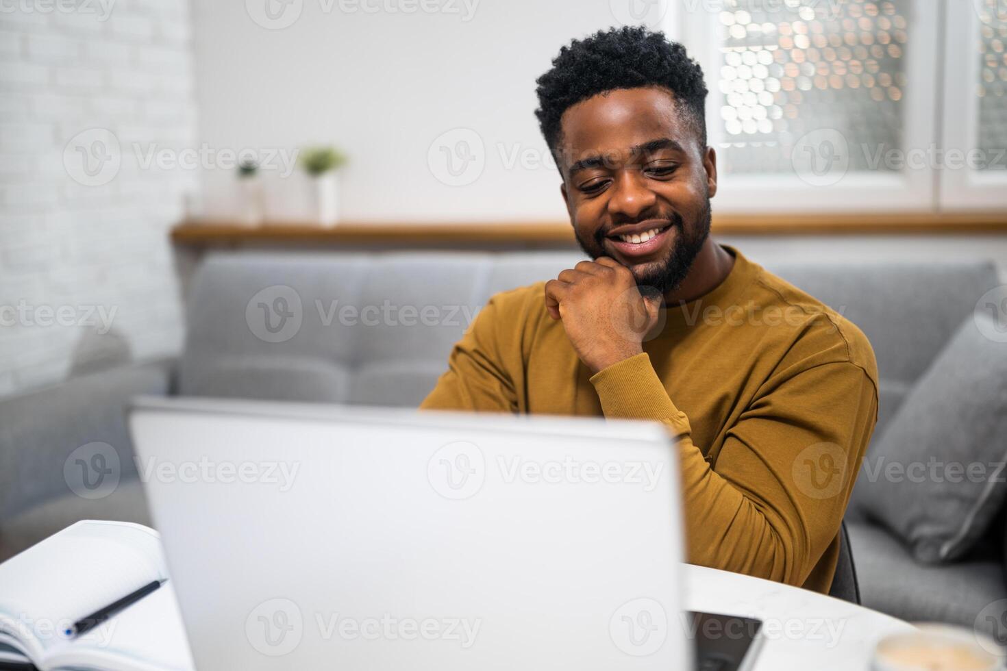 Happy African remote worker looking at the screen while engaging in a professional call, in a modern indoor setting. photo