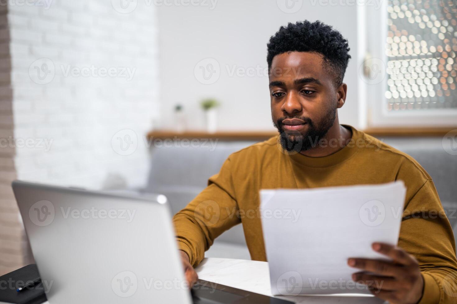 Young entrepreneur using laptop and studying business strategy, fully concentrated in a modern home office. photo