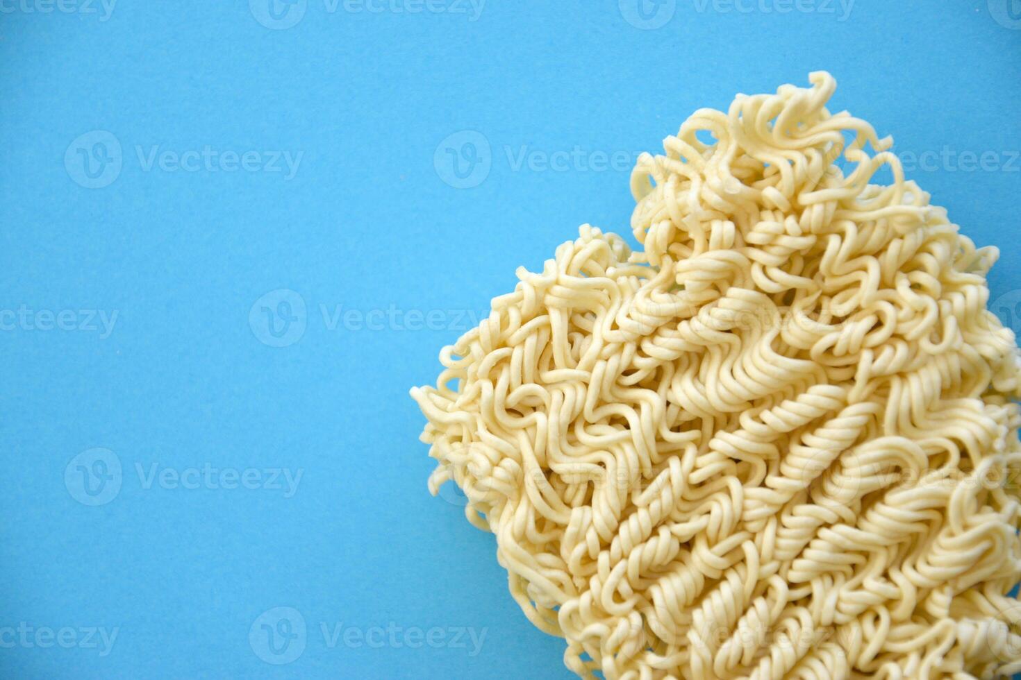 Raw instant noodles on blue paper background photo