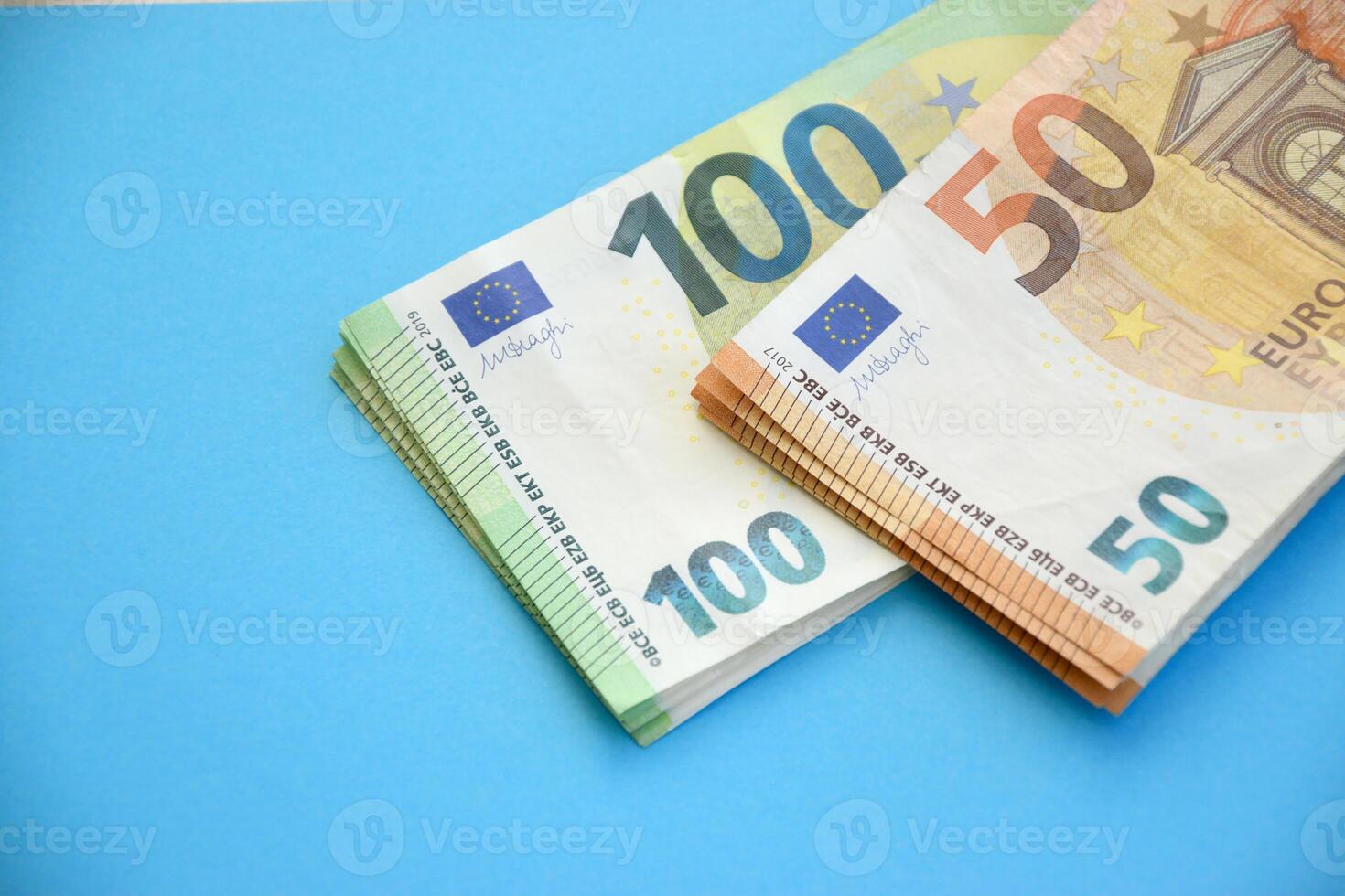 Many banknotes of 100 and 50 bills on light blue paper background photo