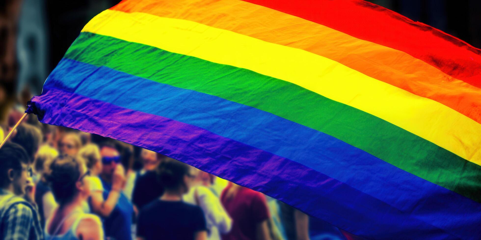 A rainbow pride flag waves with a crowd in the background, celebrating diversity and love. photo