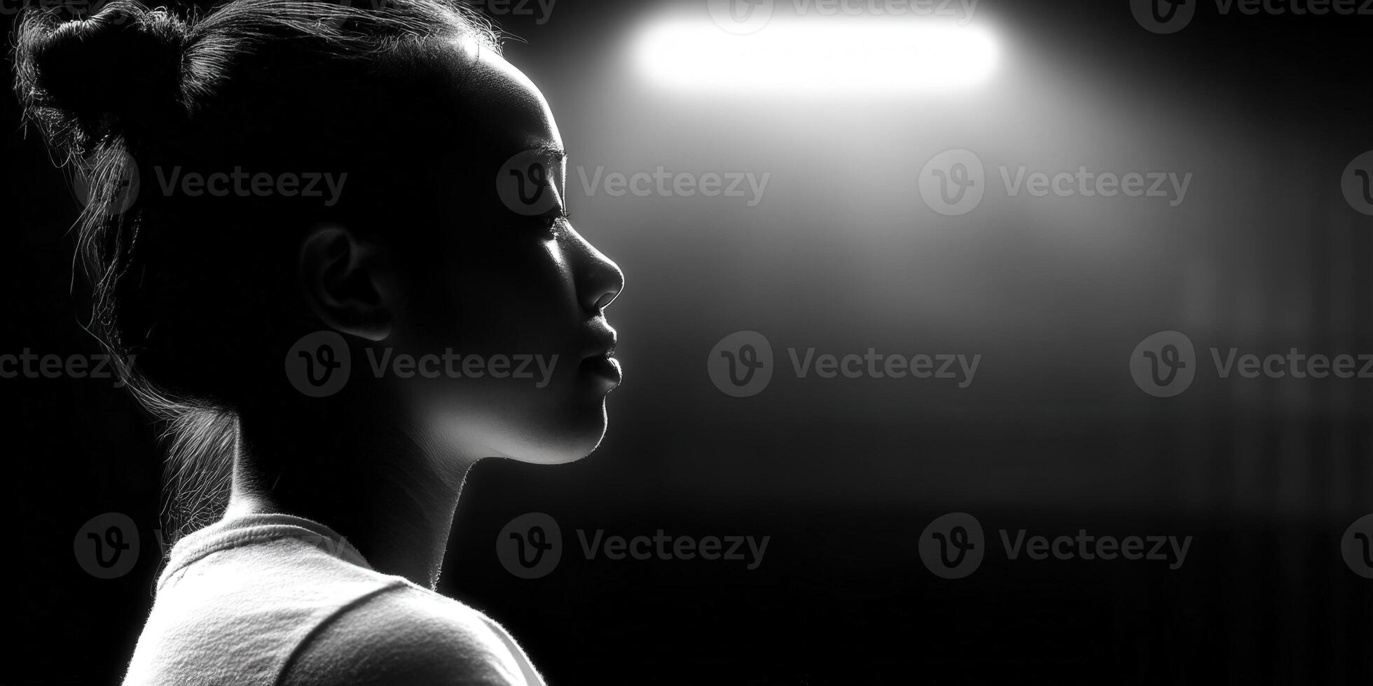 A striking black and white profile portrait of a woman under dramatic lighting. photo