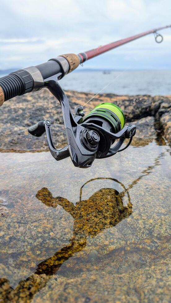 Spinning Fishing Rod with reel on Coastal Rocks with Ocean in Background Outdoor Angling Scene, Coastal Fishing Adventure photo