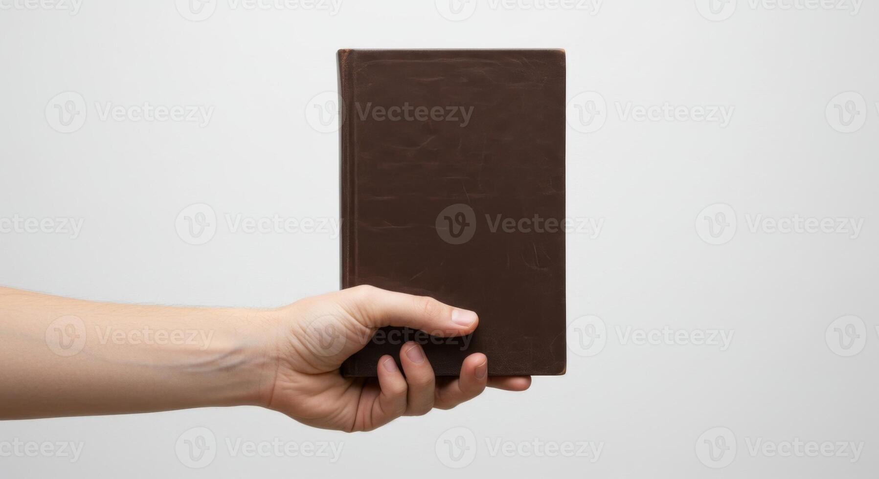 Hand Holding a Brown Book Against White Background, Focused on the Text and Cover Detail. photo