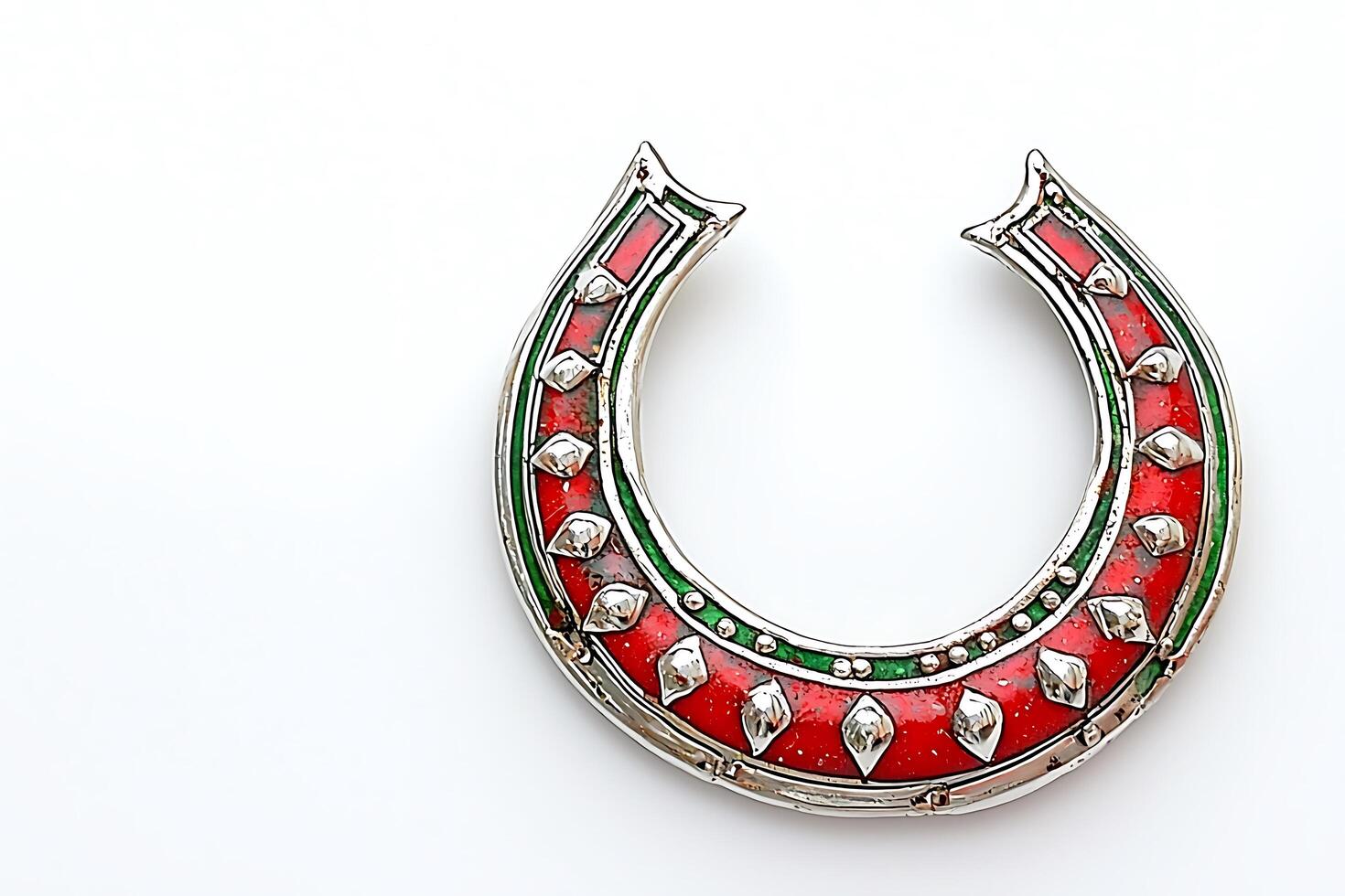 Ornate Horseshoe-Shaped Enamel Jewelry Red, Green, and Silver Detail. A close-up shot of a unique horseshoe-shaped piece of jewelry with intricate enamel work. photo