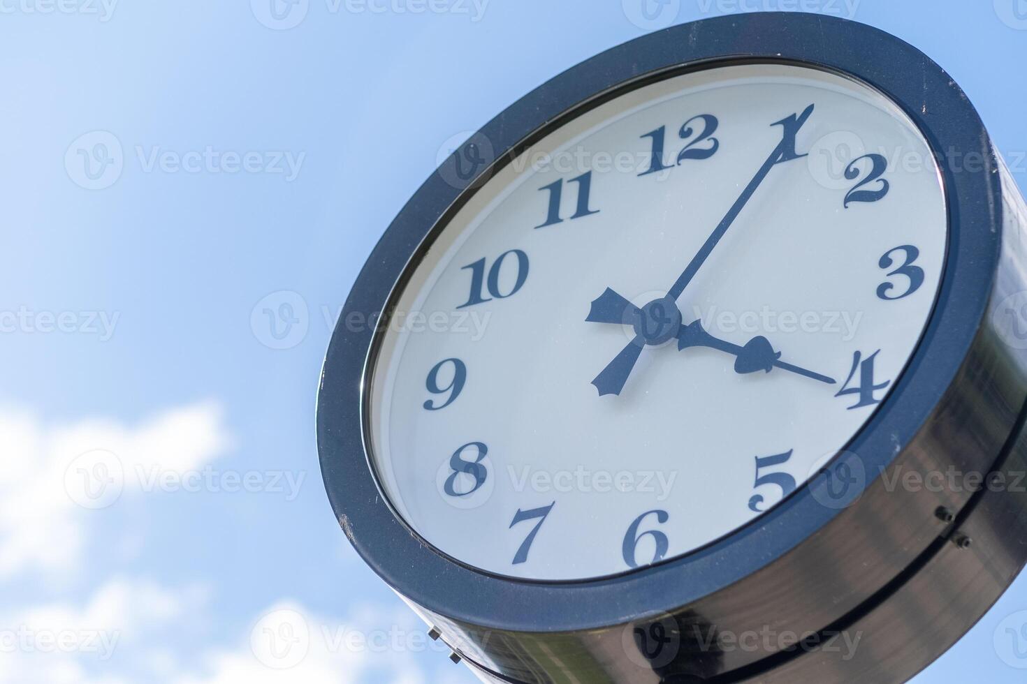 Clock Displaying Four Oclock Against a Clear Blue Sky With Scattered Clouds in a Park Setting During the Afternoon photo