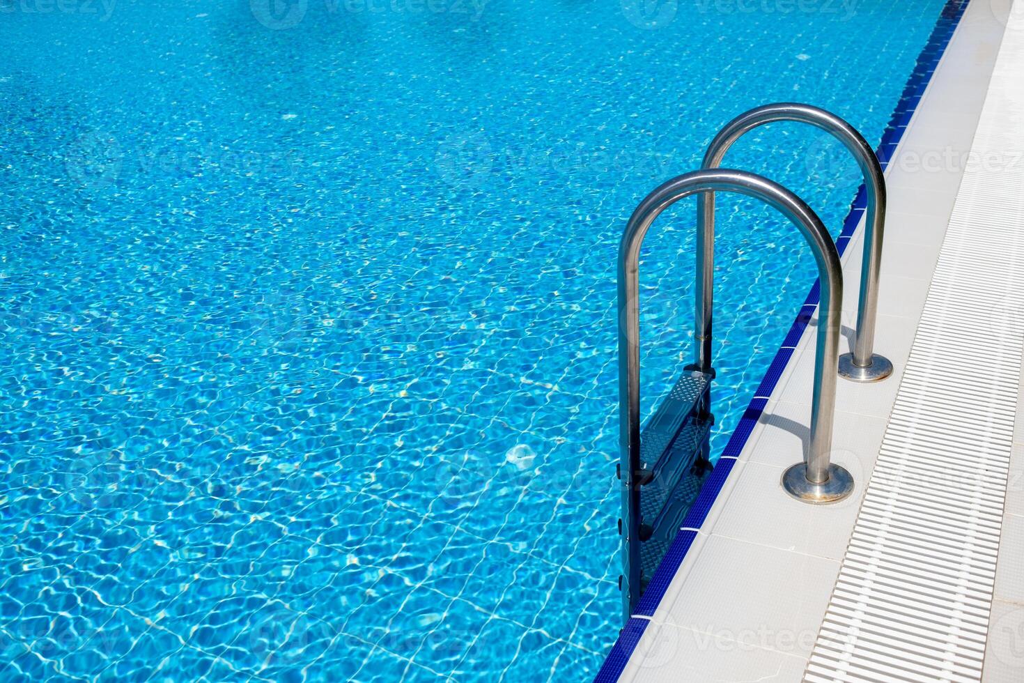 Sparkling Blue Swimming Pool With Metal Ladder on a Sunny Day Inviting Relaxation and Enjoyment photo
