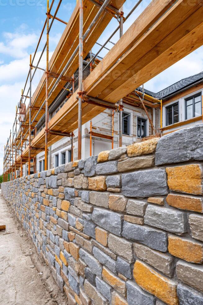 Scaffolding over building with stone wall during construction photo