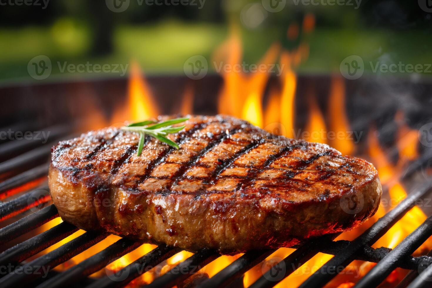 Delicious beef steak grilling on barbecue with flames and rosemary photo