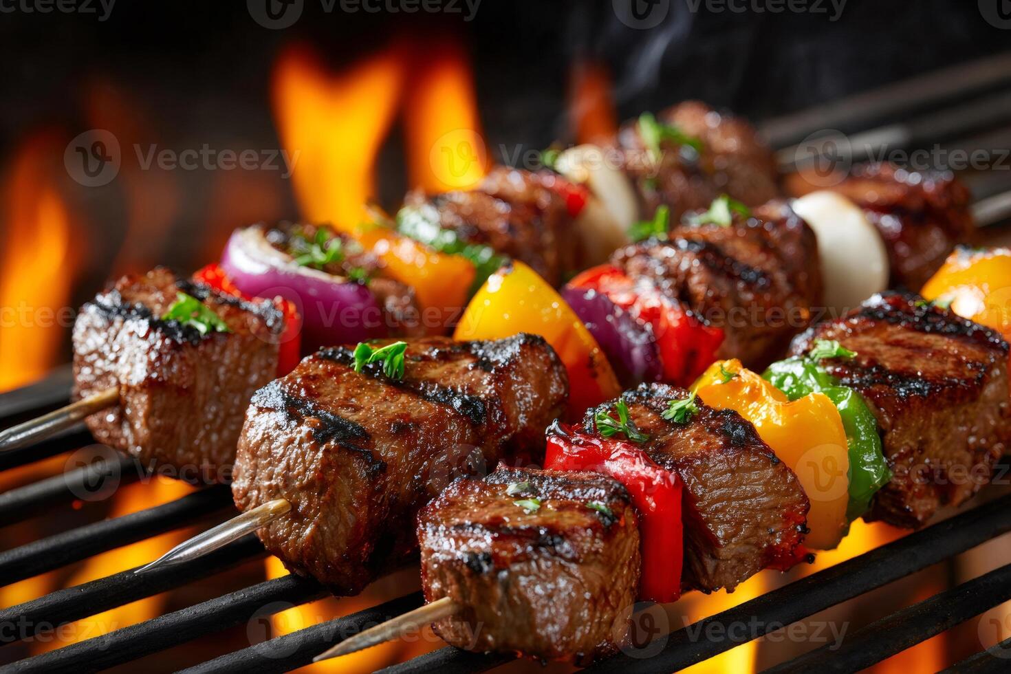 Beef and vegetable skewers are grilling on a barbecue with open flames photo