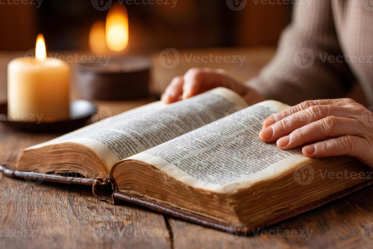 Senior woman reading holy book by candlelight near fireplace photo